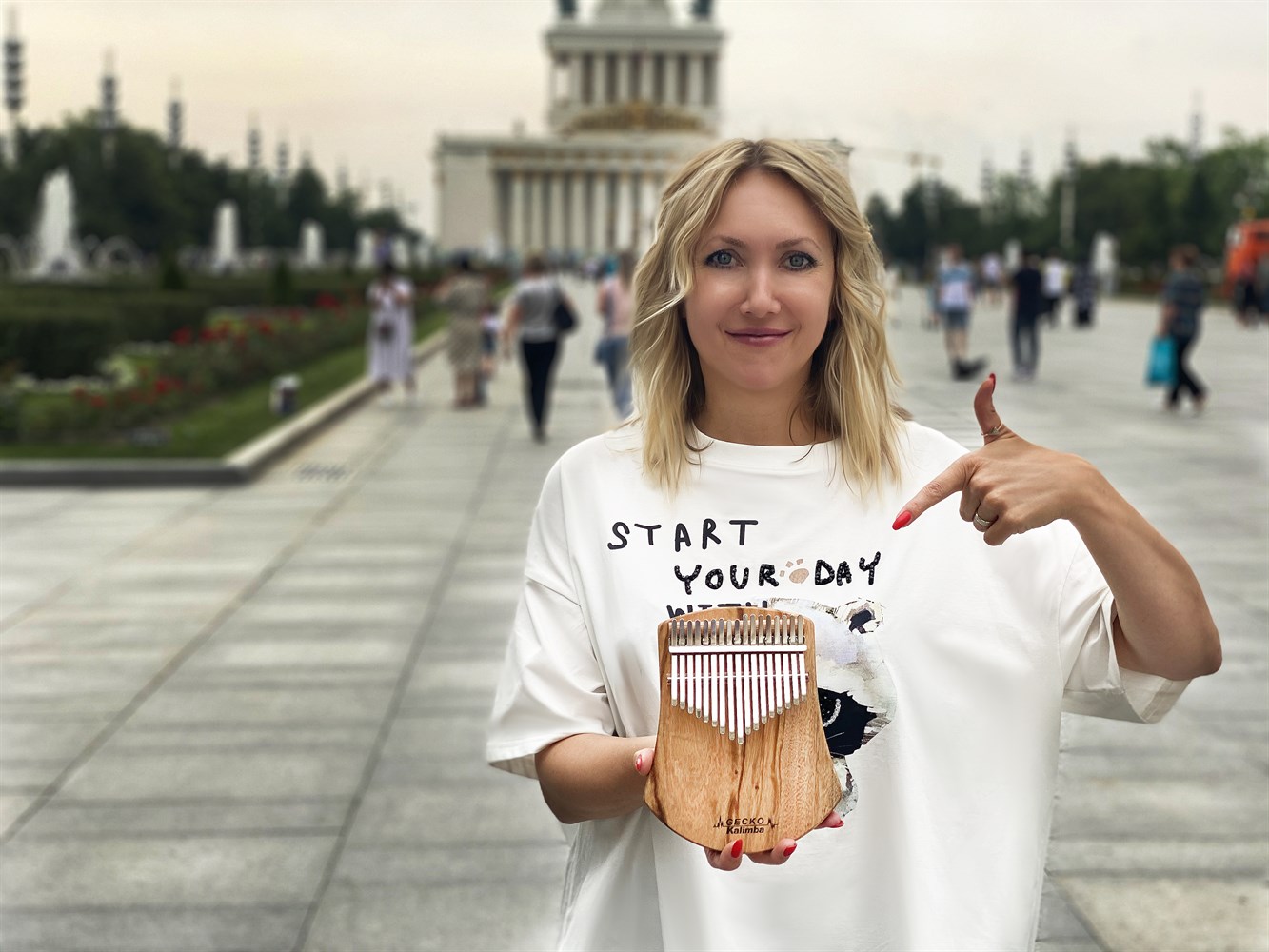 Femme tenant un kalimba en bois Gecko, instrument de musique africain à lames métalliques.